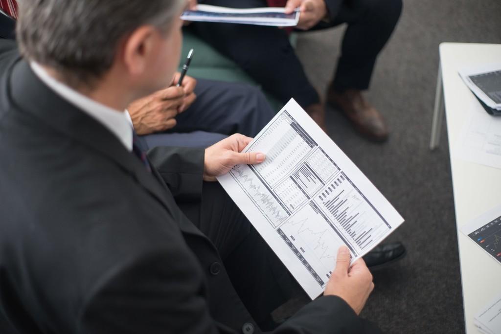 Professionals reviewing printed financial charts and valuation exhibits during a meeting