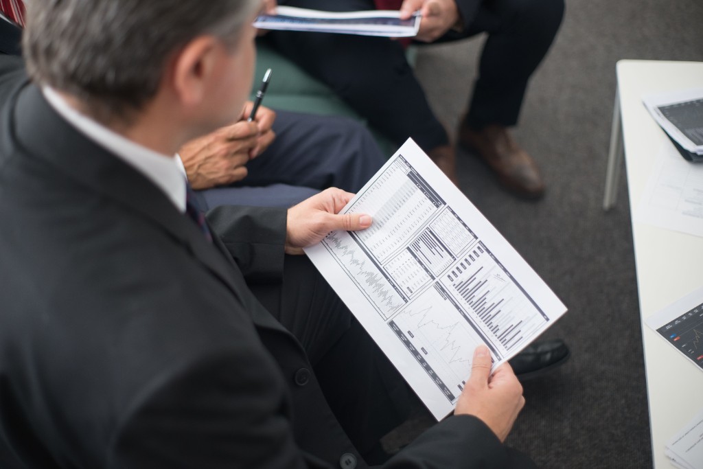 Professionals reviewing printed financial charts and valuation exhibits during a meeting